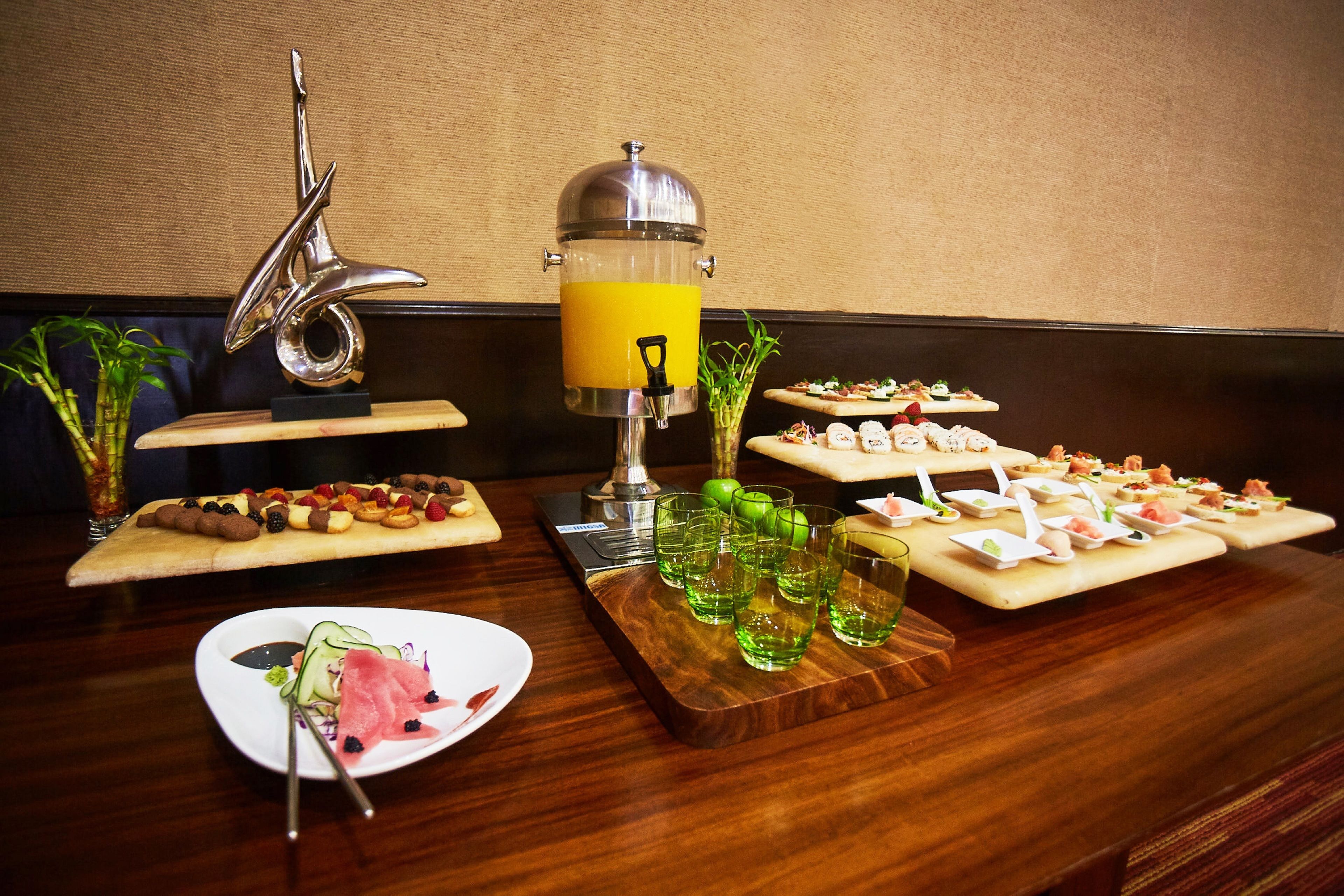 A buffet table with various food items and a juice dispenser.