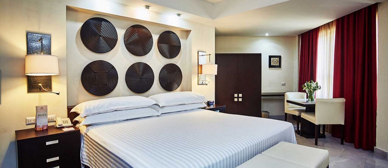 Habitación de hotel con una cama grande, mesitas de noche, un escritorio y una silla.