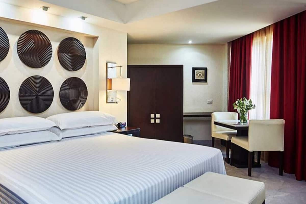 A hotel room with a large bed, bedside tables, a desk, and a chair.