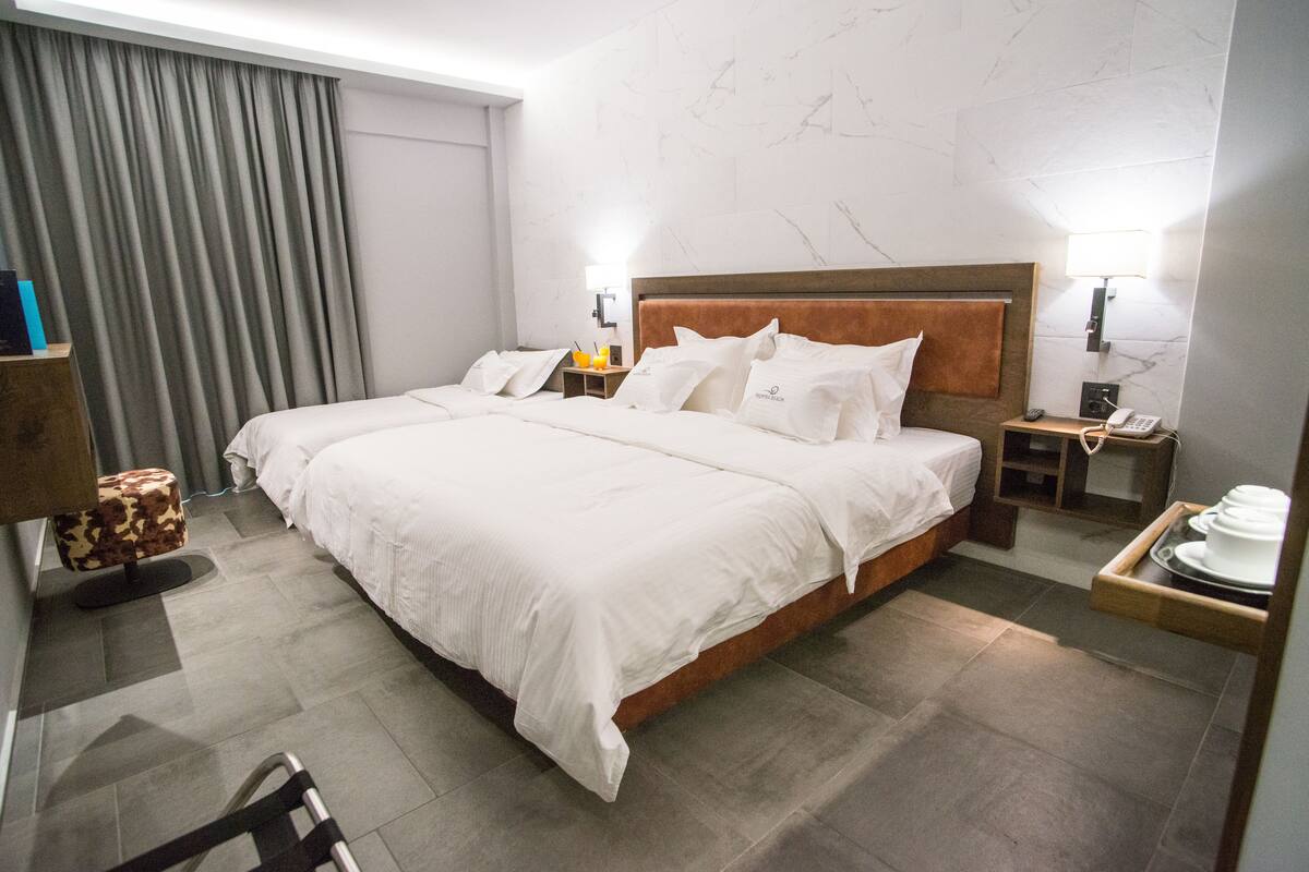 Habitación de hotel con una cama grande, dos mesitas de noche, una lámpara y una bandeja con platos.