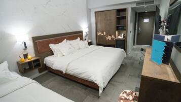 Habitación de hotel con una cama grande, un armario de madera, un escritorio con computadora y un pequeño rincón de descanso.