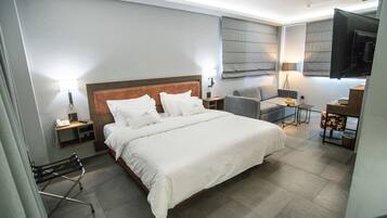Ett modernt hotellrum med en stor säng, ett skrivbord, en stol och en TV.