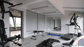 Un gimnasio moderno con diversos equipos de ejercicio, una banca y una cinta de correr.
