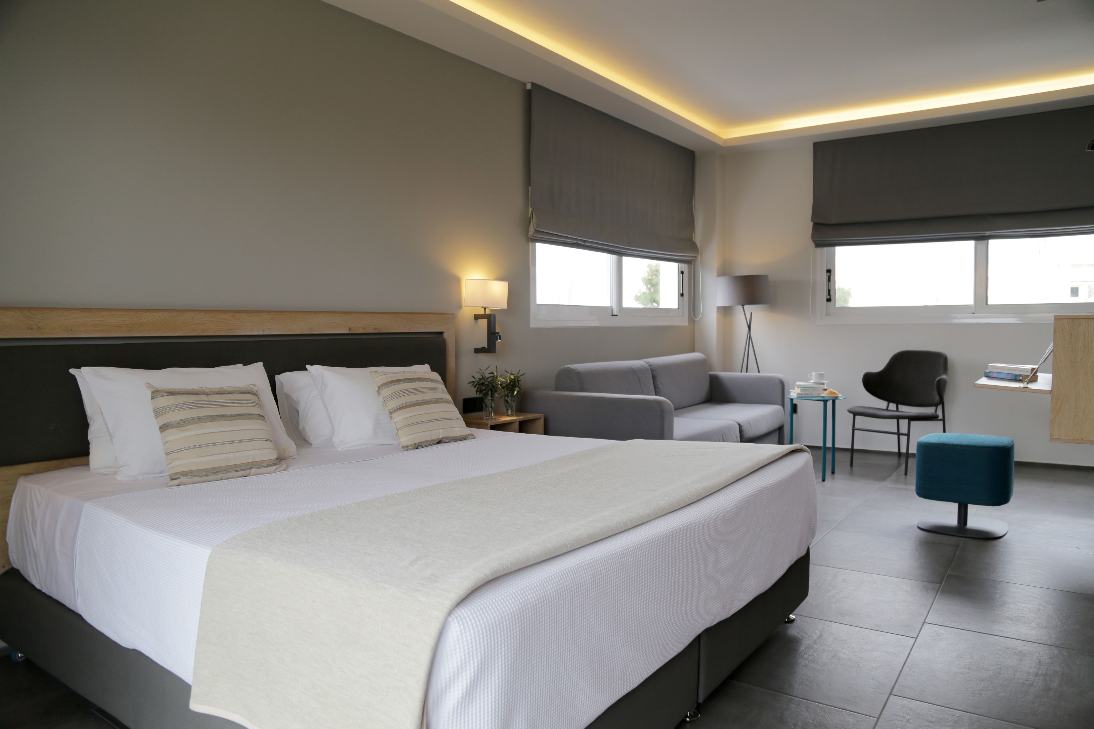 A modern hotel room with a large bed, a desk, a chair, and a small table.
