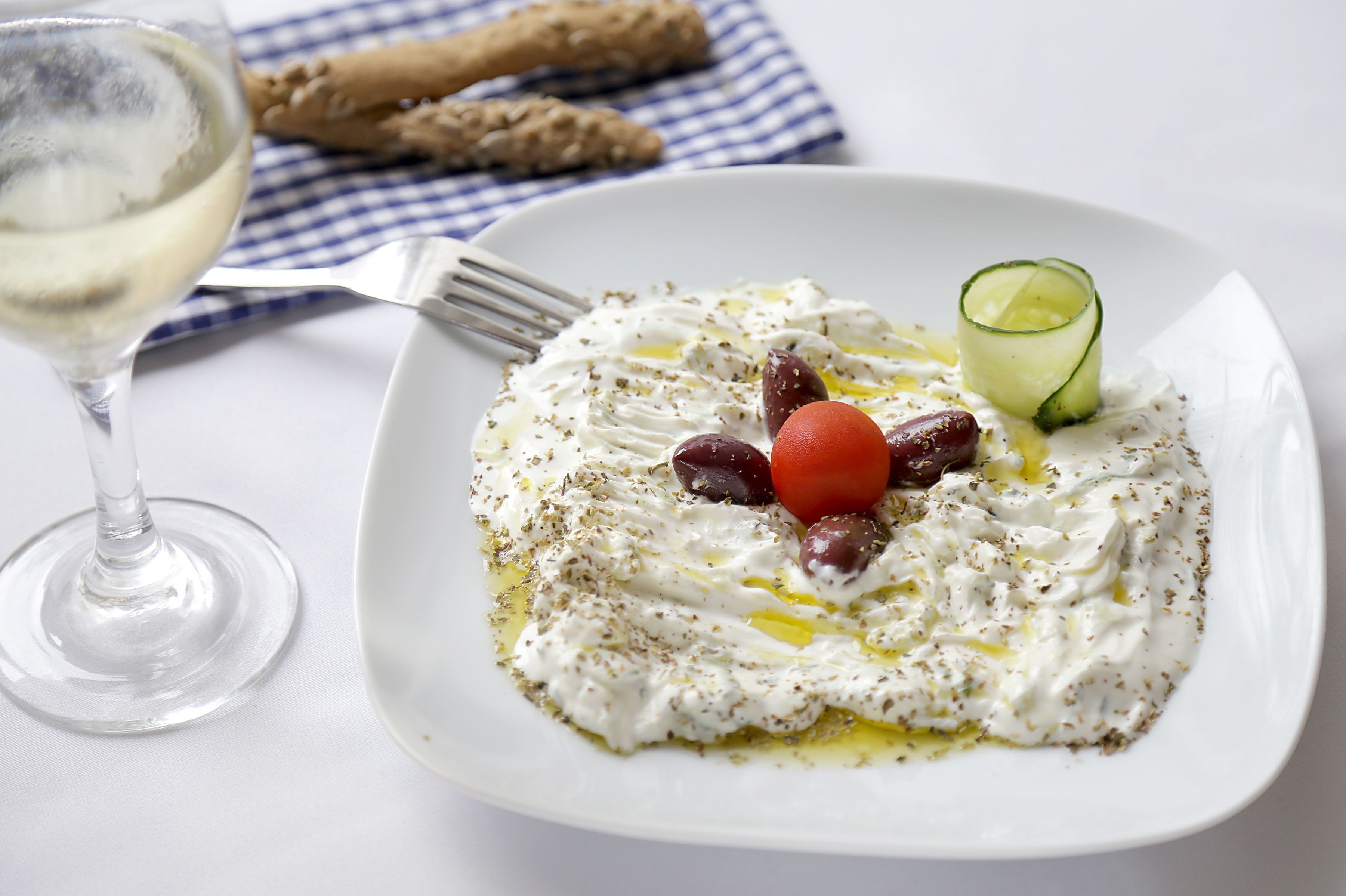 A plate of food with olives, tomatoes, and a cucumber on a white plate.