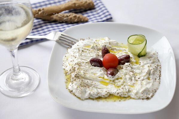 A plate of food with olives, tomatoes, and a cucumber on a white plate.