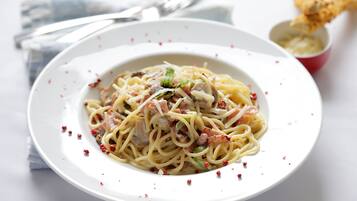 Une assiette de spaghettis avec de la viande et des légumes, une fourchette et un petit bol de sauce.