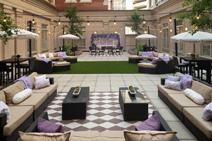 Een terras buiten met zitgedeeltes, tafels en lichtslingers.