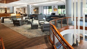 A spacious lobby with a central seating area, a reception desk, and large windows offering views of the outdoors.