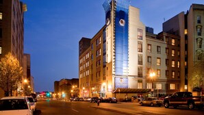 A hotel with a modern glass facade, a prominent clock tower, and a sign for 'DoubleTree by Hilton'.