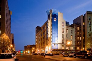 Een hotel met een moderne glazen gevel, een opvallende klokkentoren en een bord met 'DoubleTree by Hilton'.
