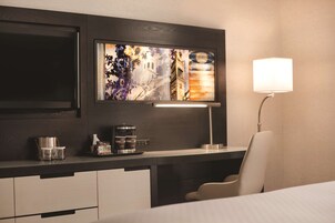 Een hotelkamer met een modern bureau, een flatscreen televisie, een koffiezetapparaat en een lamp.