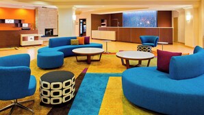 Una hall moderna con divani blu, un camino in pietra, una reception e un tappeto colorato.