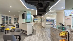 A modern restaurant with a bar area, seating, and a display of fruits. - Fairfield Inn & Suites Lake Buena Vista in Marriott Village (Orlando)