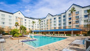 A hotel with a swimming pool, lounge chairs, and palm trees. - Fairfield Inn & Suites Lake Buena Vista in Marriott Village (Orlando)