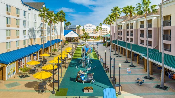 A hotel courtyard with outdoor seating, palm trees, and a chessboard. - Fairfield Inn & Suites Lake Buena Vista in Marriott Village (Orlando)