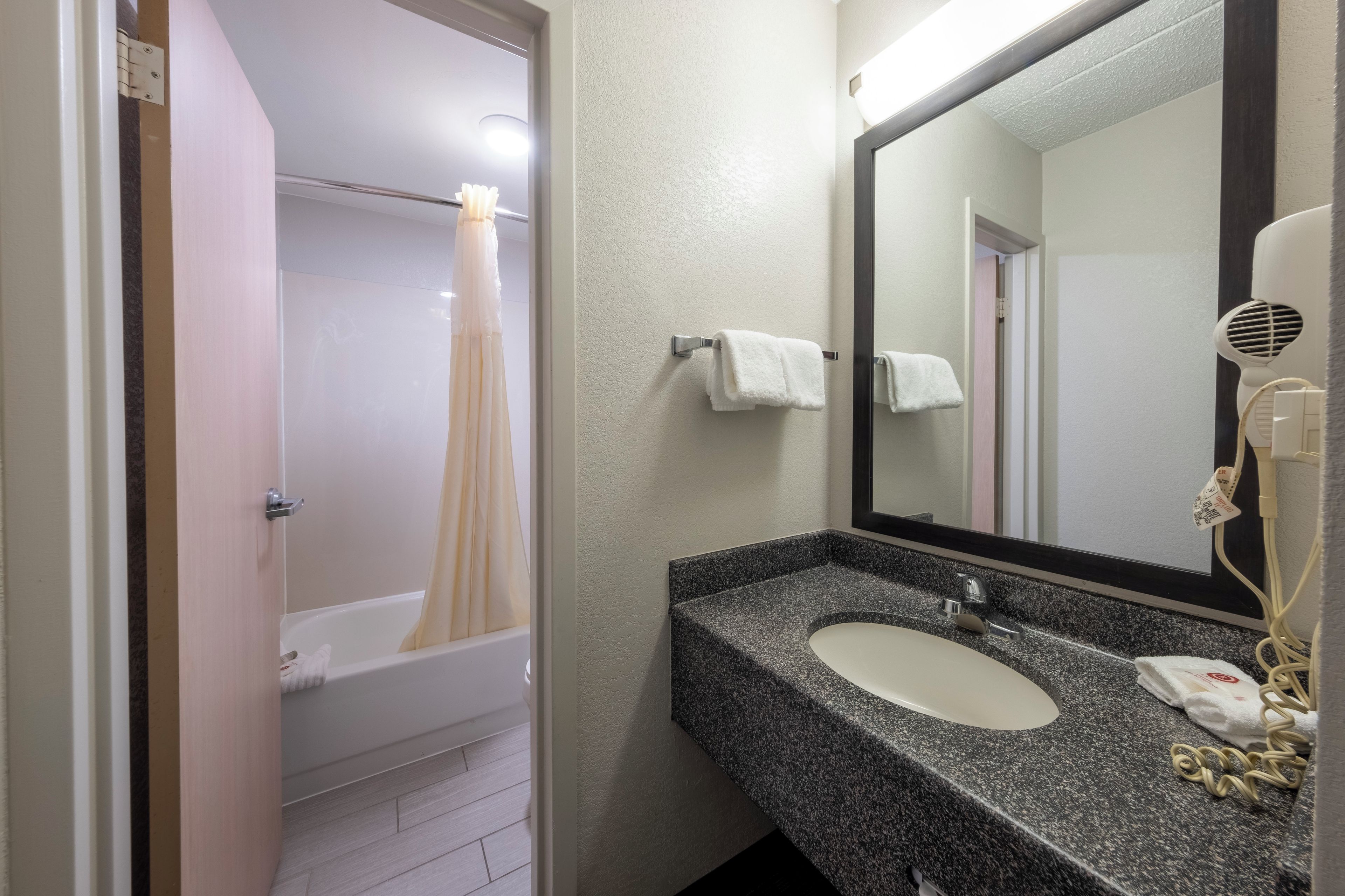 Un baño con bañera, lavabo, espejo y secador de pelo.