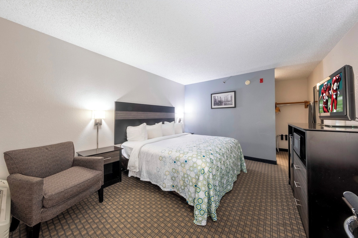 Une chambre d’hôtel comprenant un lit, une chaise, un bureau, une commode et un téléviseur.