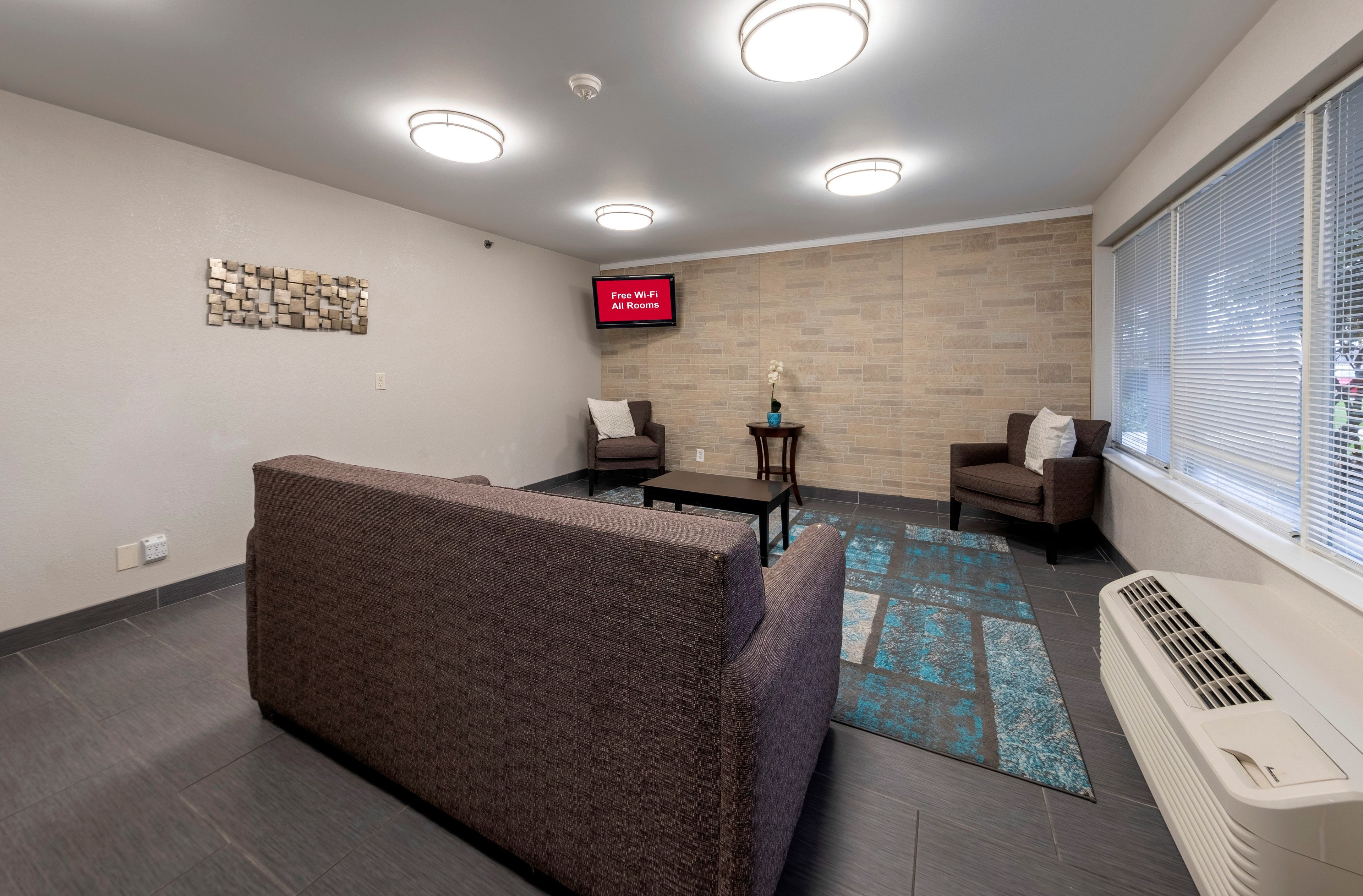 A modern living room with a sectional sofa, two armchairs, a coffee table, and a flat-screen TV displaying 'Free Wi-Fi All Rooms'.