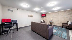Een moderne wachtruimte met een receptiebalie, zitplaatsen en een aan de muur bevestigde televisie.