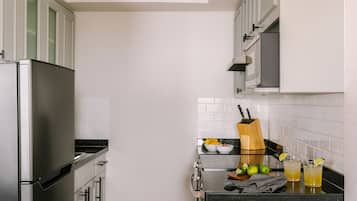 Una cocina moderna con electrodomésticos de acero inoxidable, armarios blancos y encimera negra.
