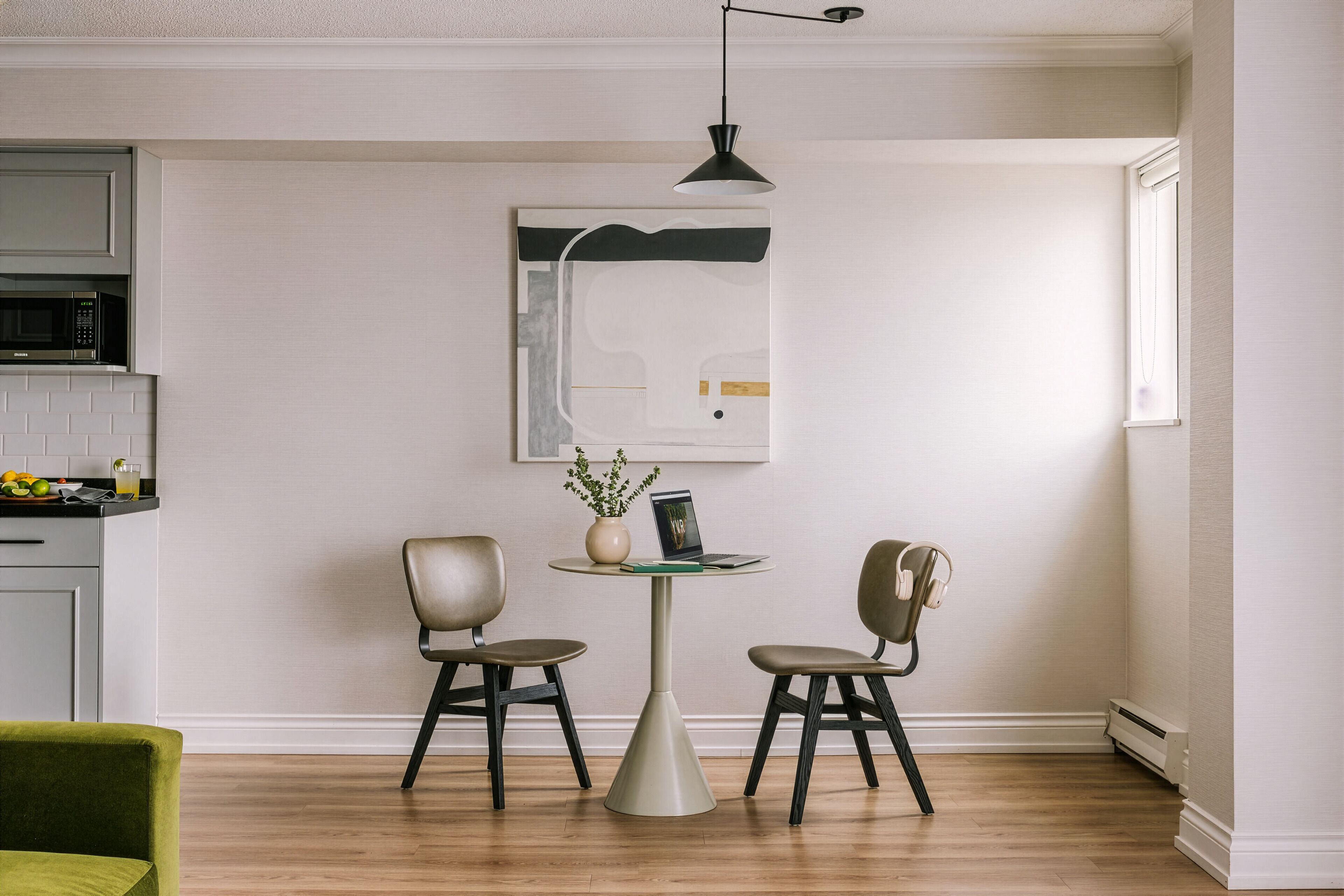 A modern kitchen with a microwave, a dining table with two chairs, and a pendant light.