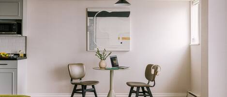 A modern kitchen with a microwave, a dining table with two chairs, and a pendant light.