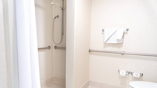 A bathroom with a shower, toilet, and towel rack.