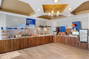 A breakfast area with a counter, bakery section, and signs indicating breakfast options. - HOLIDAY INN EXPRESS & SUITES INDIANAPOLIS - EAST by IHG (Indianapolis)