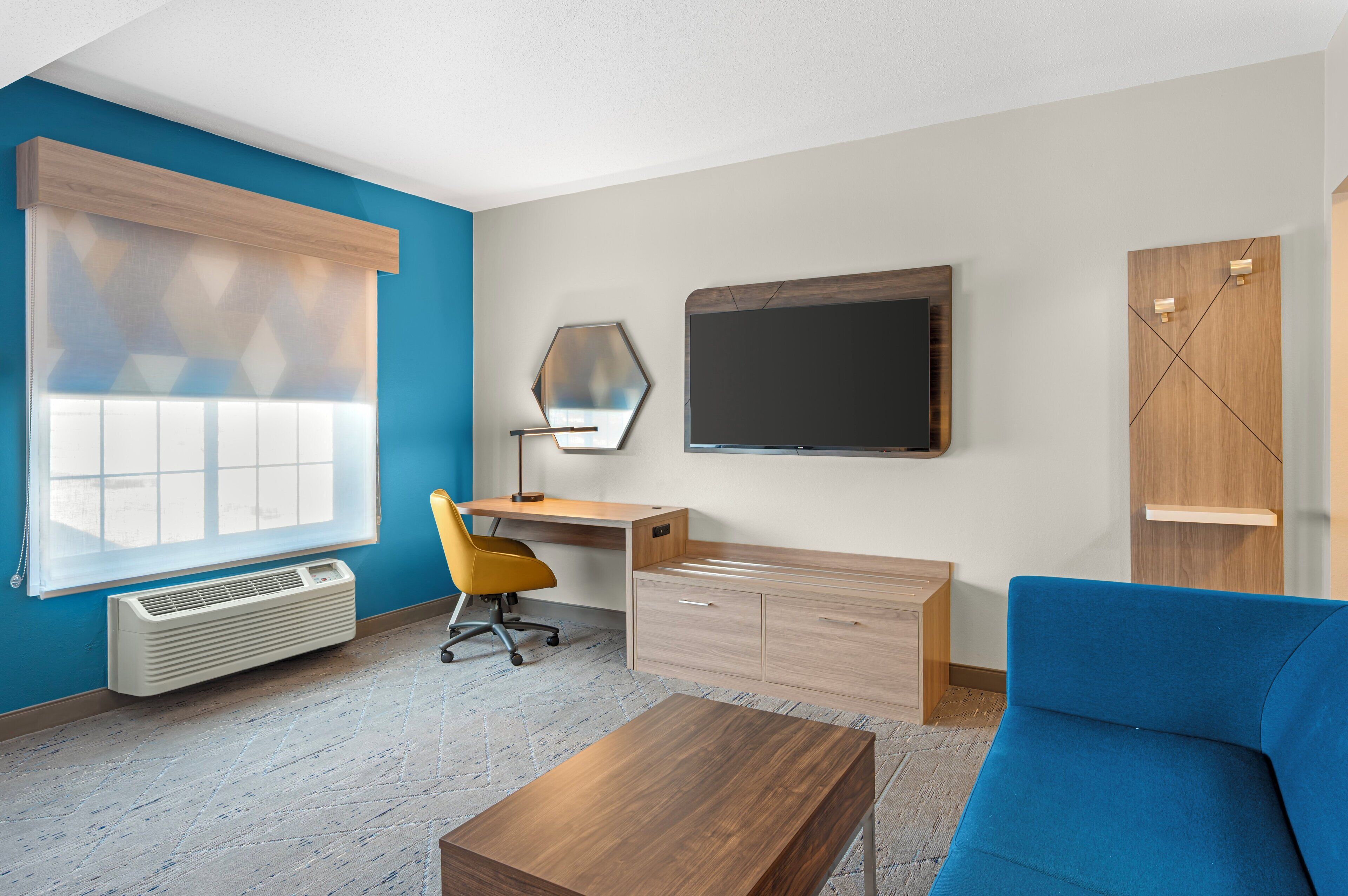 A modern room with a desk, chair, sofa, and a large window.