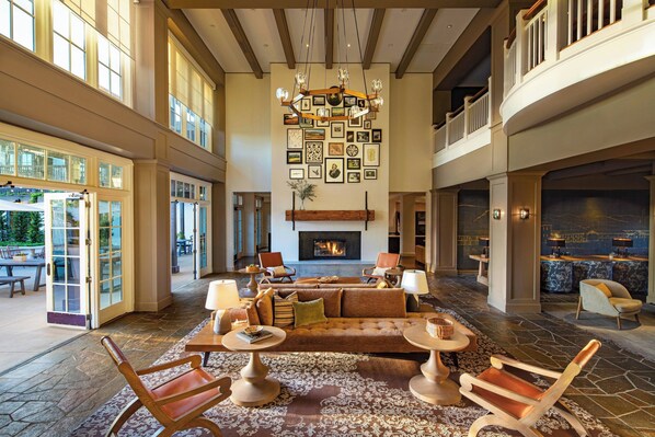 A spacious lobby with a large seating area, a fireplace, and a wall adorned with framed pictures.