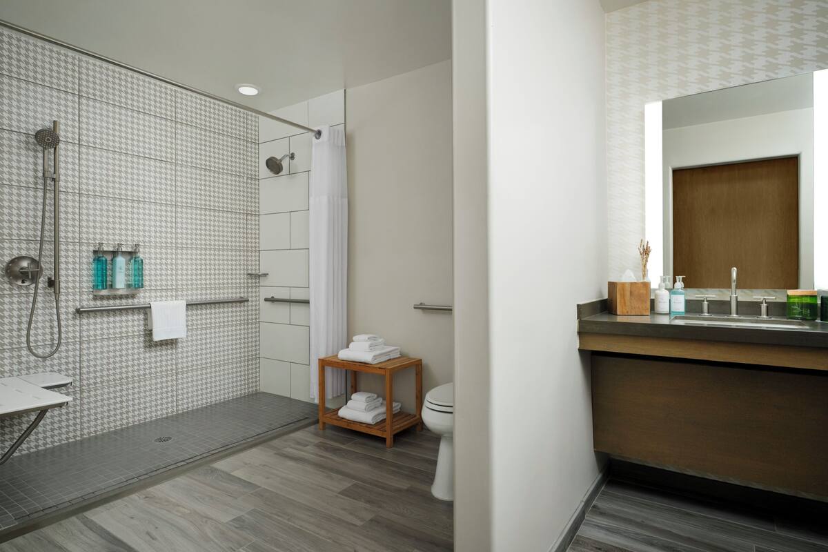 Een moderne badkamer met een douche, toilet en wastafel.