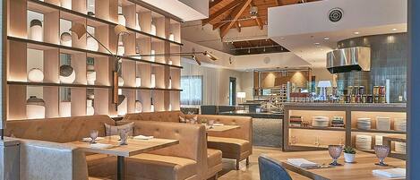 A modern restaurant with high ceilings and exposed beams, featuring a variety of seating options including booths and tables.