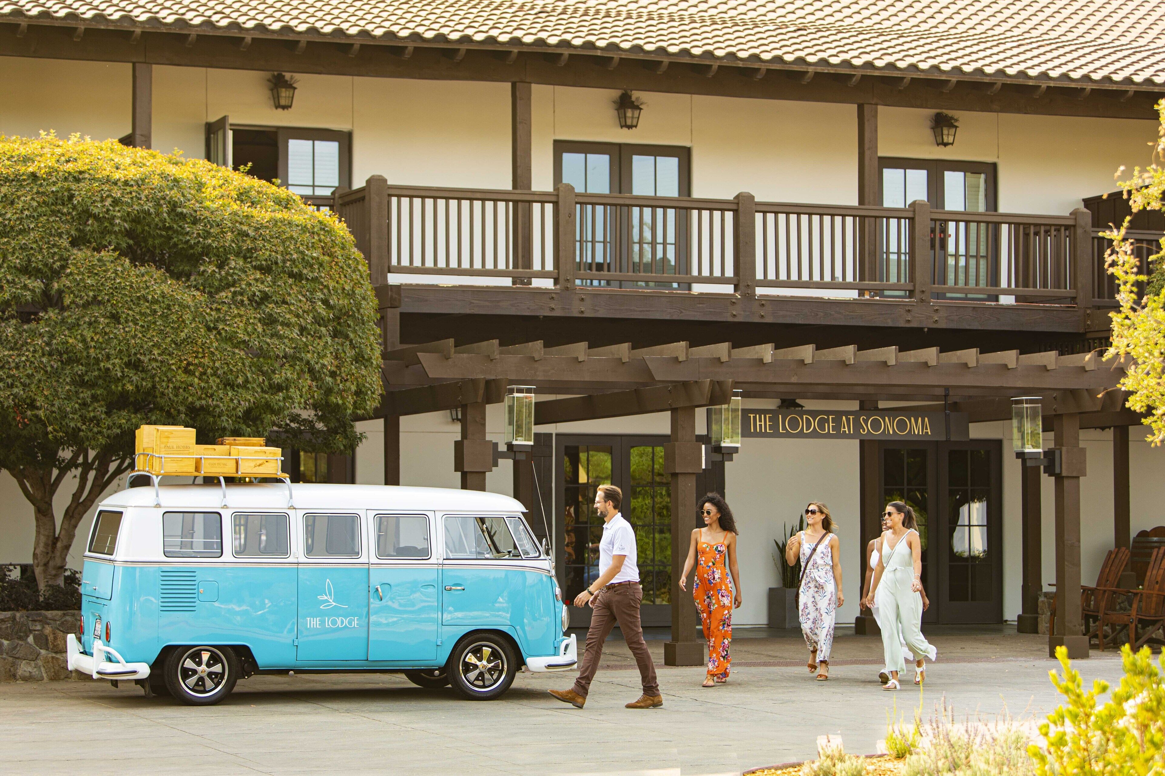 A blue van parked in front of a building with a balcony and a sign reading "The Lodge at Sonoma".