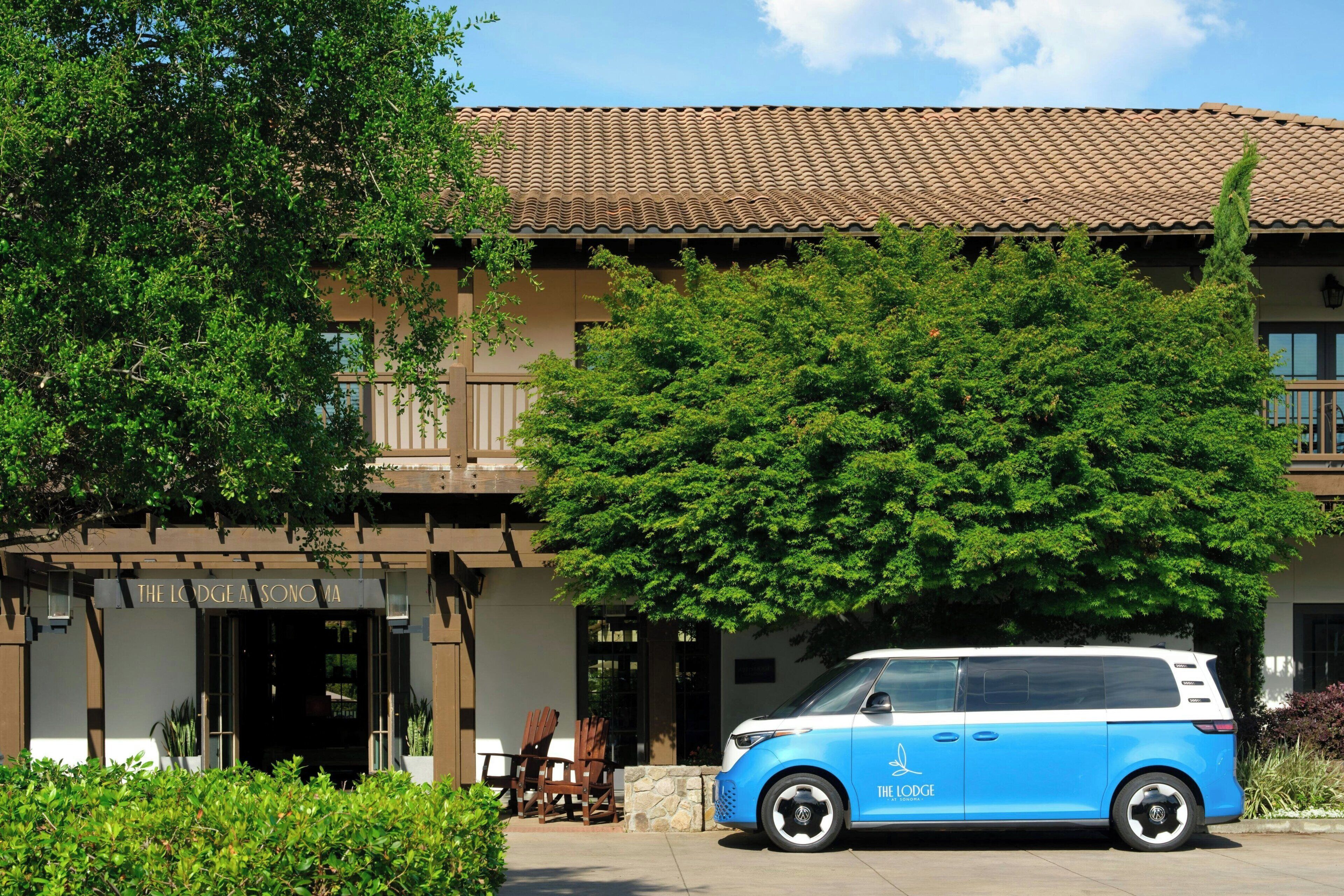 A building with a tiled roof, a blue van parked in front, and a sign reading 'The Lodge A Sonoma.'