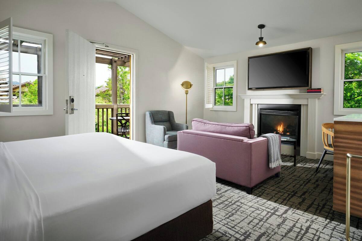 Een hotelkamer met een bed, een open haard, een televisie en een balkon.