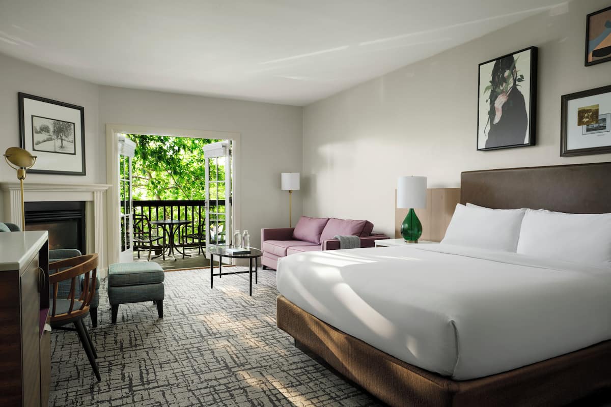 Een hotelkamer met een groot bed, een bureau, een stoel, een bank, een tafel en een open haard.