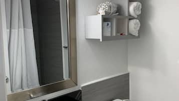Un baño moderno con un lavamanos negro, inodoro blanco y un espejo con luces. Hay un toallero con toallas sobre el inodoro.
