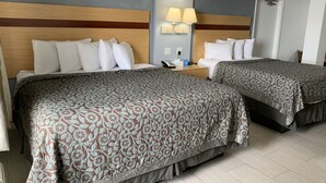 Habitació d'hotel amb dos llits, cadascun amb un llençol estampat de flors, un panell de fusta al capçal i una nit de nit amb una làmpada.
