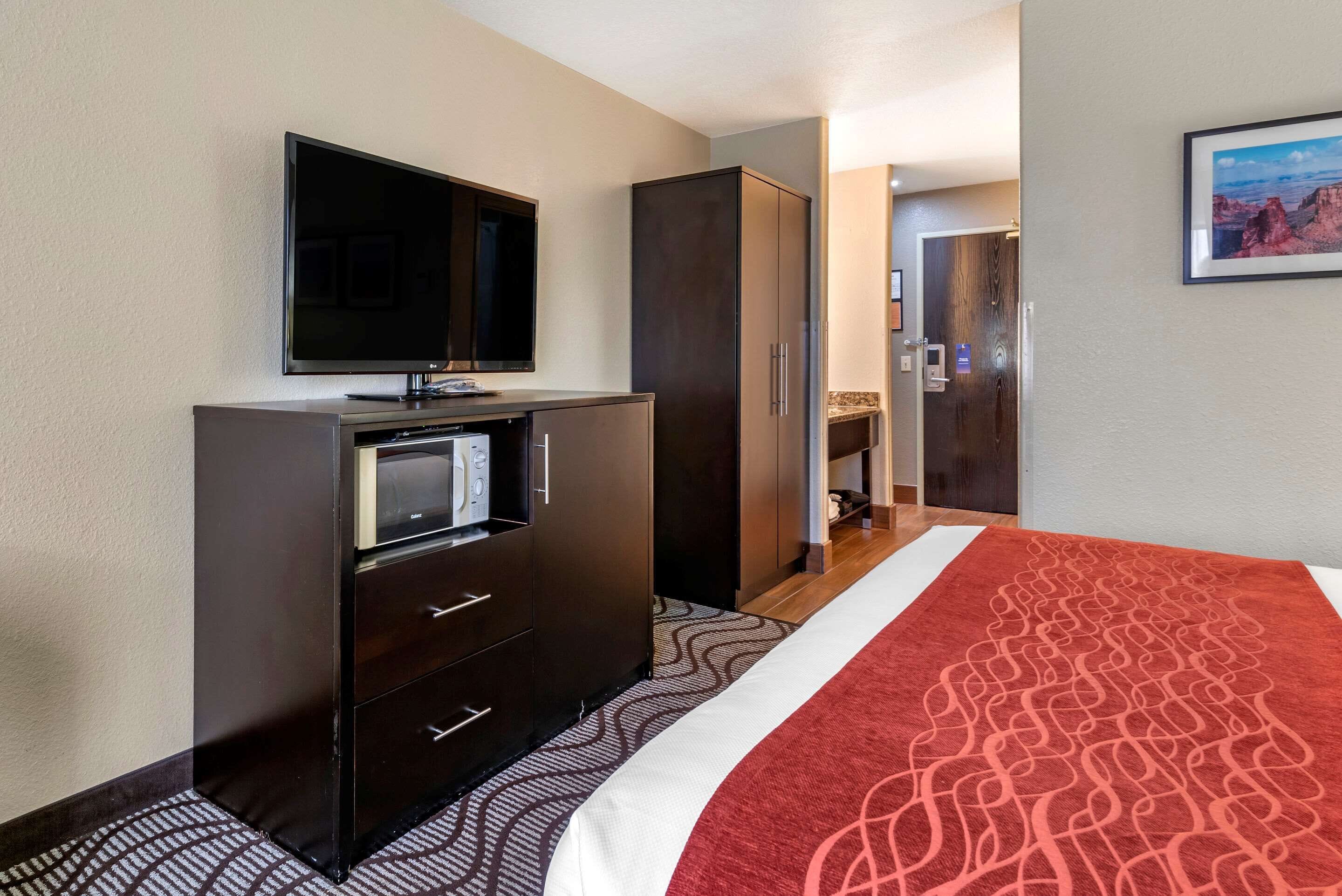 A hotel room with a bed, a television, a minibar, and a wardrobe.