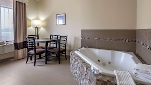 A hotel room with a dining area, a large bathtub, and a window with curtains. - Comfort Inn & Suites Fruita - Grand Junction (Fruita)