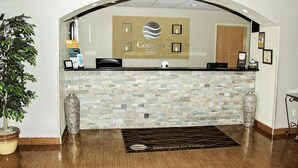 A reception area with a stone wall, a reception desk, a potted plant, and a welcome mat. - Comfort Inn & Suites Fruita - Grand Junction (Fruita)