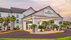 A Wingate by Wyndham hotel with a covered entrance, palm trees, and a parking lot. - Wingate by Wyndham Biloxi/Ocean Springs (Biloxi)