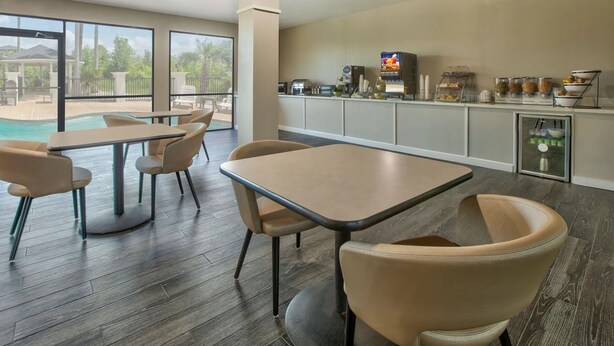 A modern dining area with a pool view, featuring a bar and breakfast station. - Wingate by Wyndham Biloxi/Ocean Springs (Biloxi)