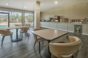 A modern dining area with a pool view, featuring a bar and breakfast station. - Wingate by Wyndham Biloxi/Ocean Springs (Biloxi)