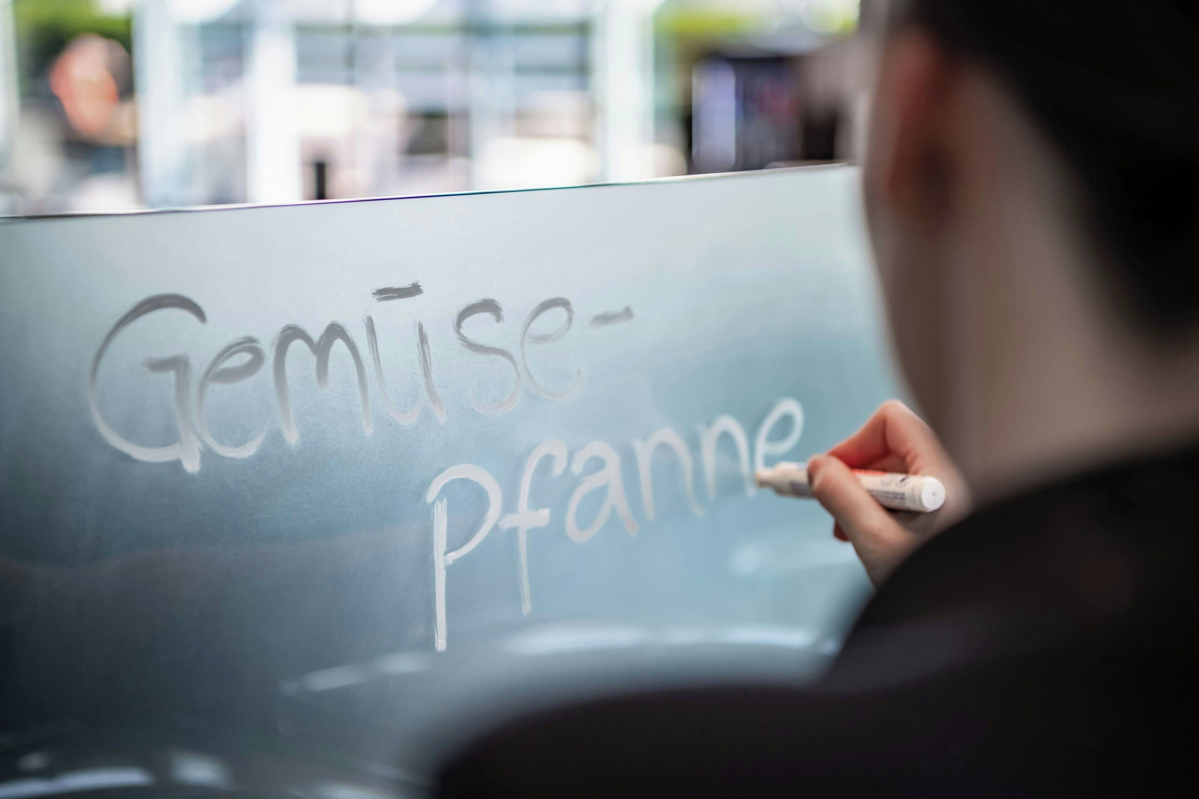 A person writing on a glass surface with a marker.