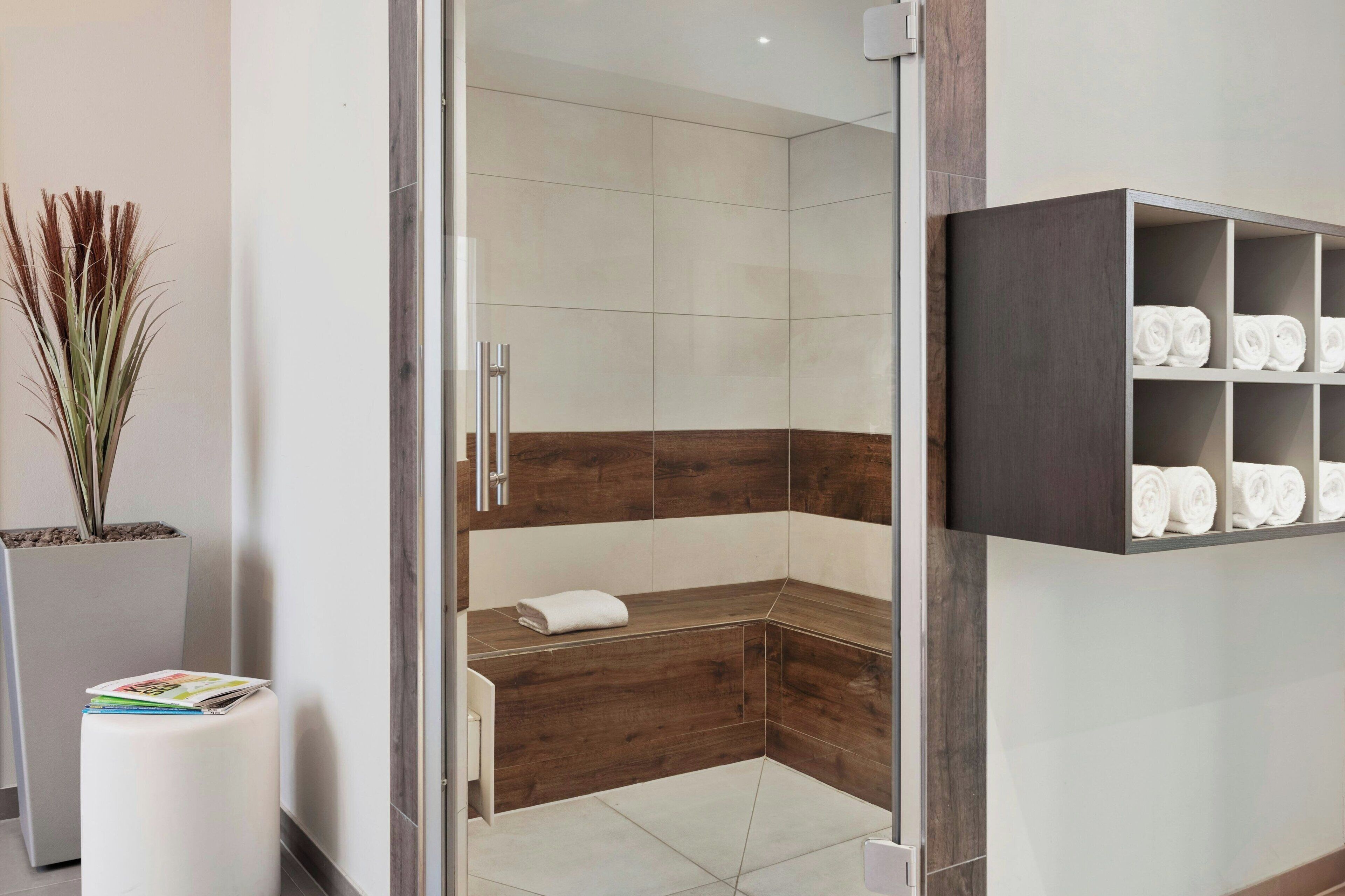 A modern bathroom with a shower, a built-in towel rack, and a magazine holder.