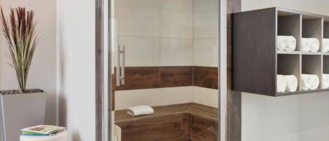 A modern bathroom with a shower, a built-in towel rack, and a magazine holder.