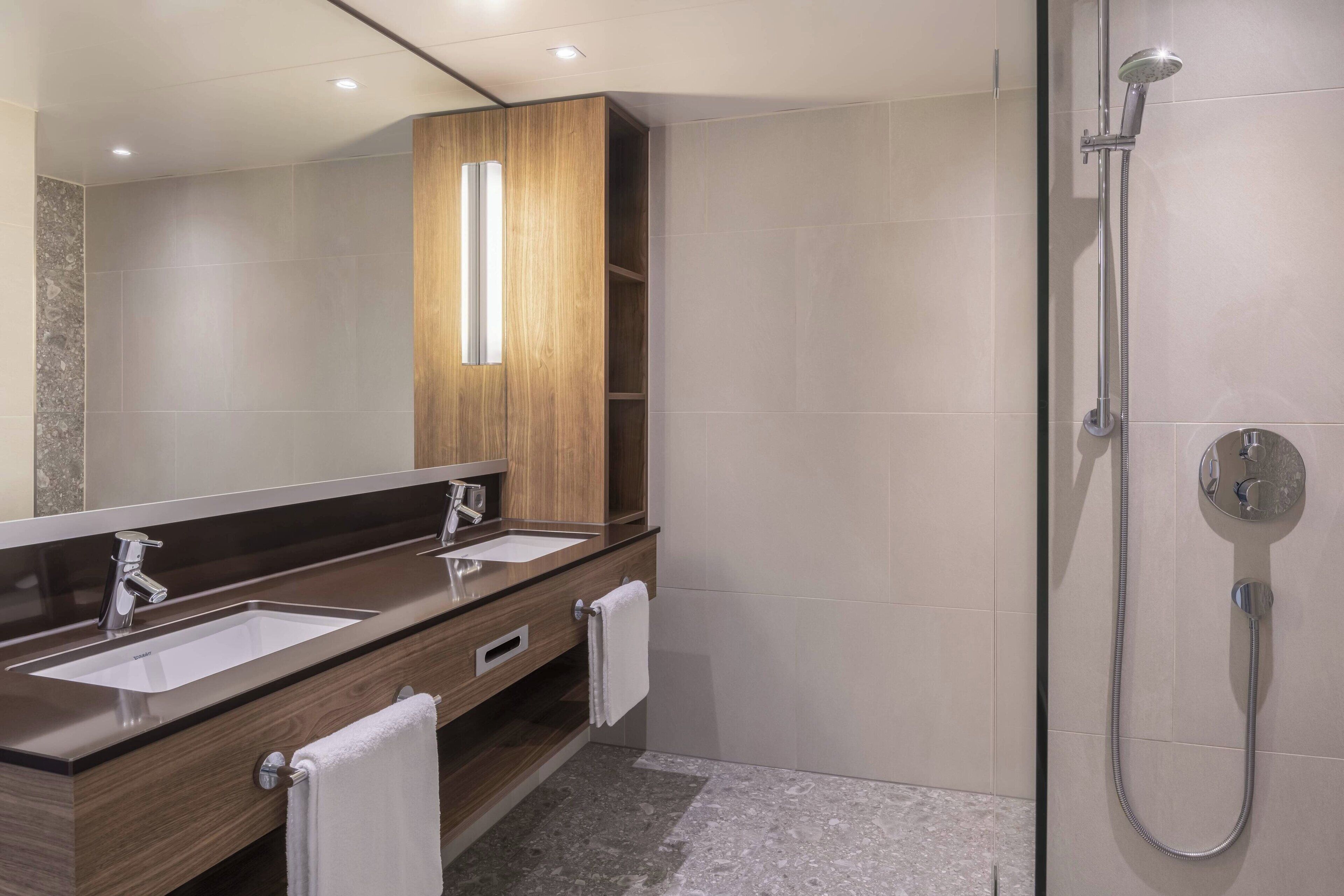 Un baño moderno con dos lavamanos, un espejo grande y una ducha.