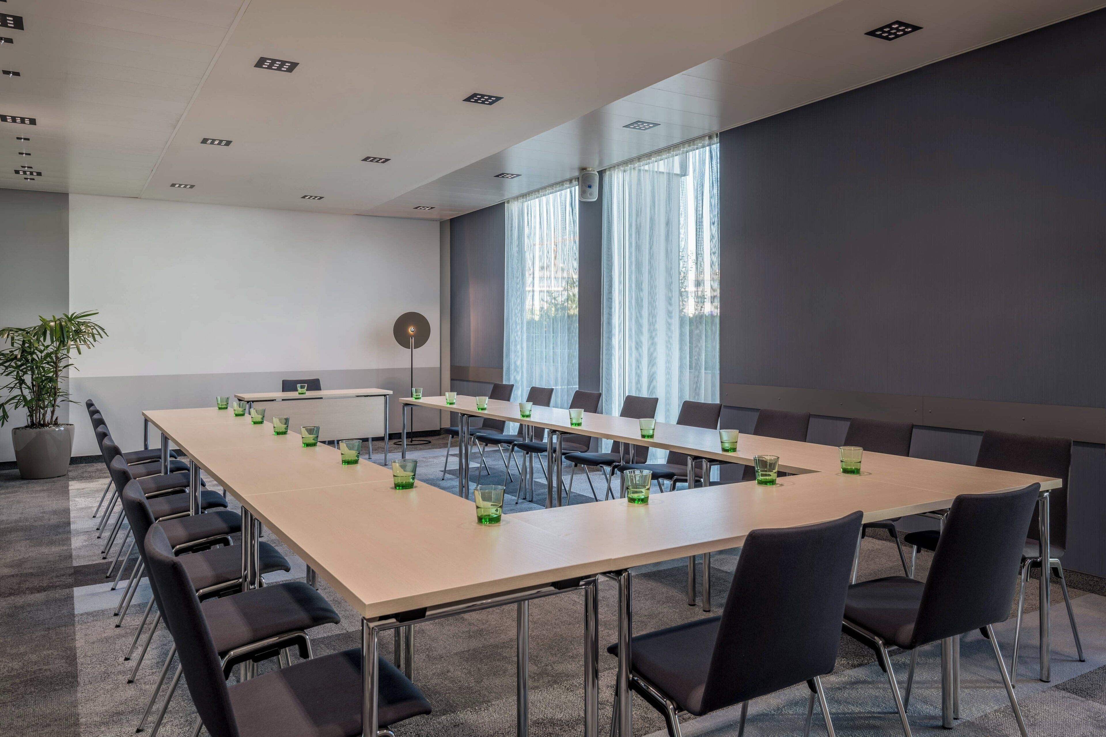 Una sala de conferencias con una larga mesa, sillas y una planta en maceta.